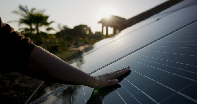 Hand touching and moving along a solar panel at sunrise