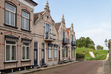 Fototapeta na wymiar Street with dike houses with stepped gables in the Dutch fortified city of Willemstad in the province of North Brabant.