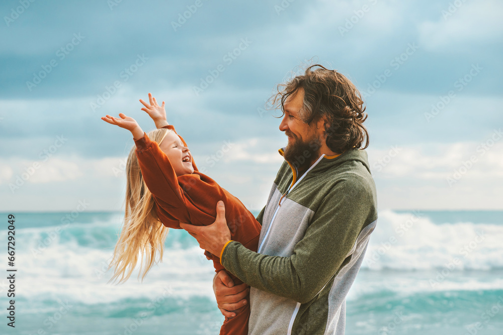 Wall mural Family fun father and daughter playing together outdoor cheerful kid with dad summer vacations lifestyle on the beach candid emotions Father's day holiday