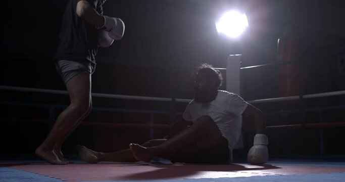 Fighter raising himself from floor after defeat. Warrior resilience gets up showing strength and effort captured in speed-ramp slow-motion at 800 fps