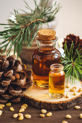 Organic essential oil, pine nuts, cedar cone on rustic wooden dark background. Concept of natural ingredients, naturopathy, herbal extracts and essence. Alternative medicine, aromatherapy