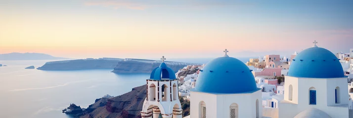 Fototapeten A rooftop in Santorini, Greece, white buildings with blue domes, overlooking the sea, sundown colors © Marco Attano