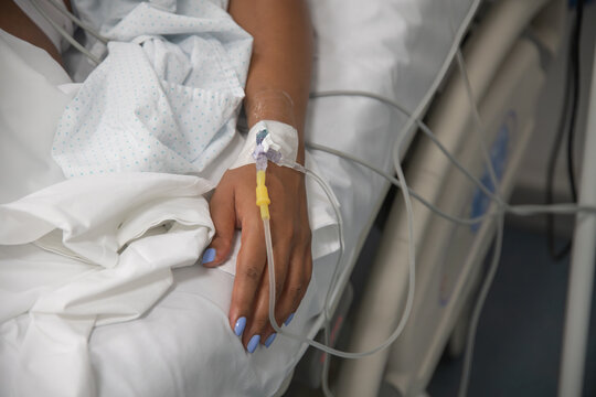Pregnant woman's hand attached to IV in hospital
