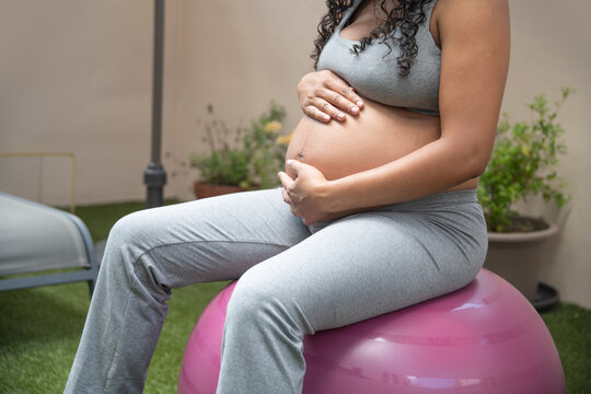Pregnant woman on exercise ball in garden