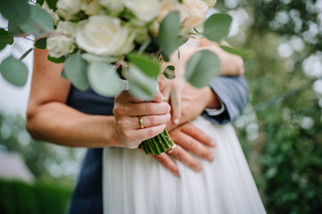 Woman in white dress holding bouquet of flowers. Bride with wedding ring on the hand. Marriage.