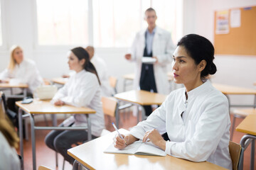 Portrait of confident asian female doctor listening lectures within refresher course. Professional development concept - obrazy, fototapety, plakaty