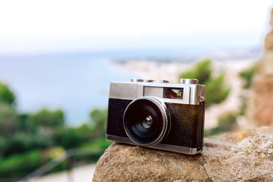 Vintage analog camera poised against oceanic background.