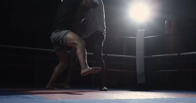 Fighters Clinching to Defend Against Strikes in Slow Motion inside ring with dramatic lighting