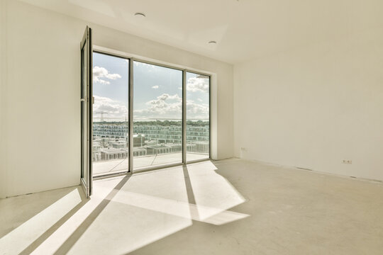 Empty room with open windows overlooking city