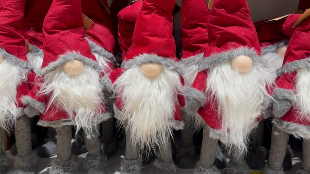 Many elves with red conical hats and white beards stand in a row next to each other. Fairy-tale dwarf brothers. A red Christmas elf decorates houses on New Year's Eve. Merry Christmas