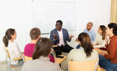 Multi-ethnic group of adult people sitting in circle and sharing ideas during class