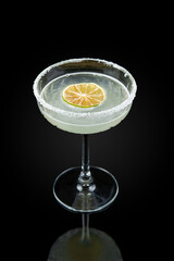 Daiquiri. Alcoholic cocktail of Cuban origin, the components of which are light rum, lime juice and sugar.  Drink in a glass on a dark background with reflection