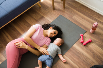 Relaxed fit mother resting with her baby after exercising