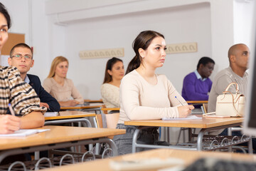 Young woman sitting at desk in classroom working during lesson at adult education class