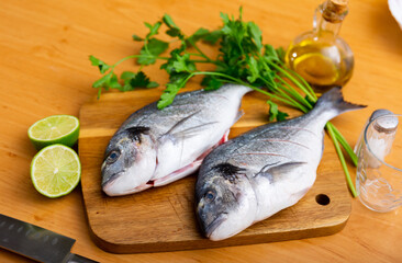 Two breams laying on cutting board with lime and parsley