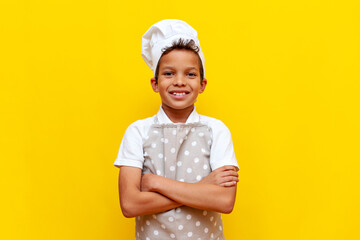 little chef child african american in uniform standing with arms crossed and smiling on yellow isolated background - obrazy, fototapety, plakaty