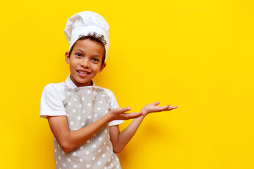 little chef child african american in uniform pointing with hands at copy space on yellow isolated...