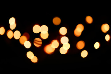 Yellow bokeh on a black background. New Year and Christmas Festive background.Warm bokeh festive...