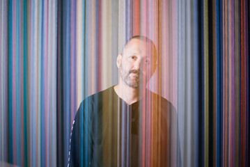 Man standing behind blurred multicolor string