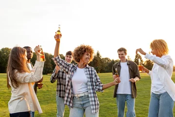 Foto op Plexiglas group of young multiracial students holding bottles of beer and dancing at outdoor party, interracial people relaxing © Богдан Маліцький