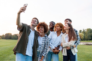 group of multiracial young people take selfies on smartphone and take pictures in the park, interracial students