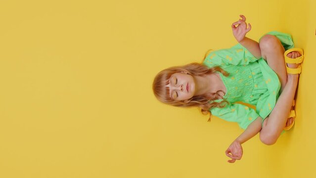 Keep calm down. Blonde child girl kid breathes deeply with mudra gesture, eyes closed, meditating with concentrated thoughts, peaceful mind, relaxing, taking a break, rest. Preteen children. Vertical