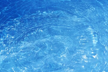 Defocus blurred transparent blue colored clear calm water surface texture with splashes reflection. Trendy abstract nature background. Water waves in sunlight with copy space. Blue watercolor shine.