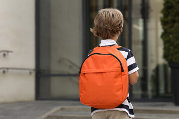 Little boy walking to kindergarten outdoors, back view. Space for text