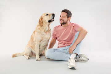 Man with adorable Labrador Retriever dog on light gray background. Lovely pet