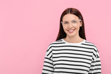 Fototapeta premium Smiling woman in stylish eyeglasses on pink background. Space for text