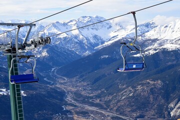 Empty chair lift for skiers and snowboarders overlooking Susa valley and Alpine village in Sauze...