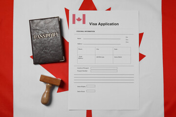 Immigration to Canada. Visa application form, wooden stamp and passport on flag, flat lay