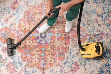 Dry cleaner's employee hoovering carpet with vacuum cleaner, above view