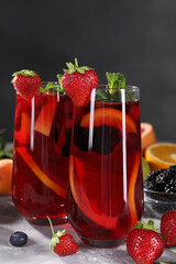 Delicious refreshing sangria and ingredients on light grey table, closeup