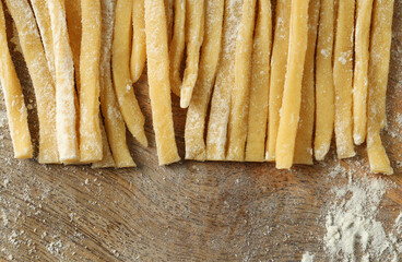 Raw homemade pasta and flour on wooden table, closeup. Space for text