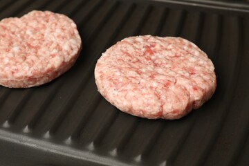 Fresh raw hamburger patties on grill pan, closeup