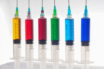 Syringes filled with colorful liquids are neatly arranged on an isolated background