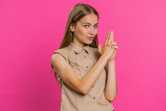 Young woman pointing around with finger gun gesture, looking confident, making choice, shooting killing with hand pistol right on target. Girl isolated alone on pink studio background. Lifestyles