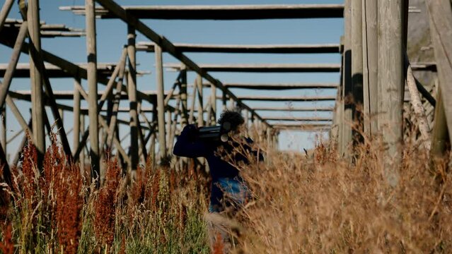 Man Walking By Stockfish Rack With Tripod