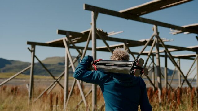 Man With Tripod Walks Near Stockfish Rack