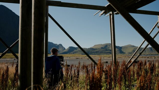 Man Near Curly Dock And Stockfish Rack Filming