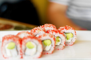 Close-up of red Philadelphia sushi rolls with eel on a blurred background, in a cozy restaurant. Japanese cuisine. Food, fast food, cafes