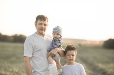 Having fun with kids, time for father and sons, family active weekend. Father and  baby walking through the woods on a sunny summer day. Dad holds his son's hand and they are fooling around