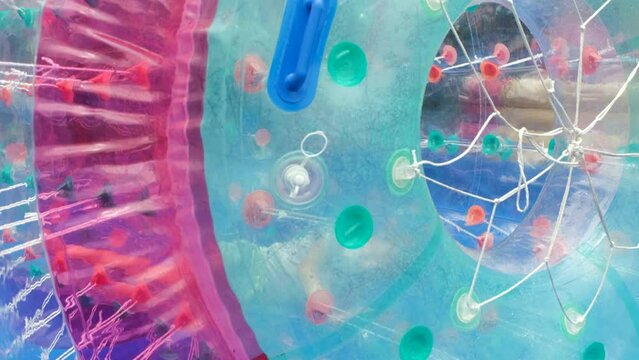 Young girl playing inside water roller at amusement park. Child having fun in zorb cylinder on the water in an inflatable pool