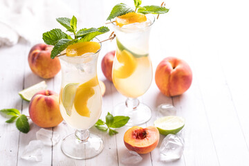 Refreshing peach mojitos surrounded by peaches, against a bright background.