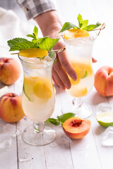 A hand reaching in to take a refreshing peach mojito, from behind.