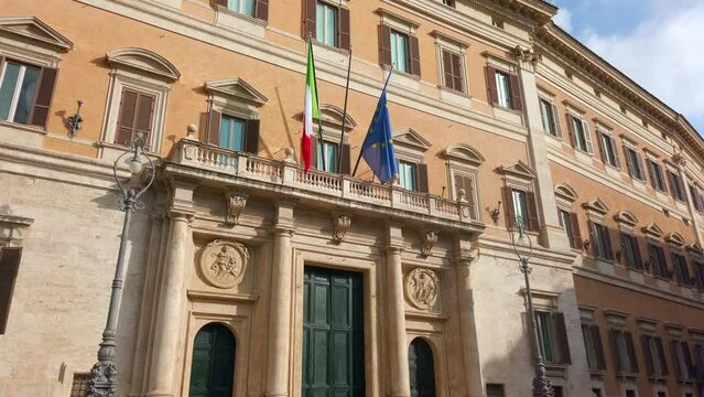 Main entrance of Palazzo Montecitorio, a palace, seat of the Chamber of Deputies, the lower house of the Italian Parliament (Rome, Italy). It displays an Italian and an European flag. Dolly move.