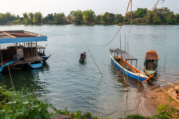 Fototapeta na wymiar Narrow boats at small Don Det Island jetty beach and entry point,4000 Islands,Champasak Province of southern Laos.