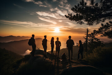 Silhouette of a group of friends standing on top of a mountain during sunset.