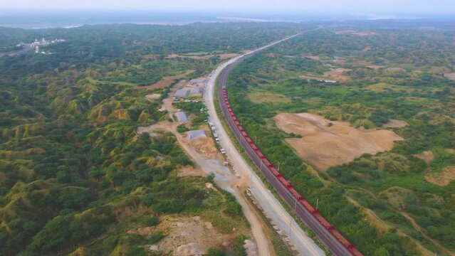 Aerial Drone shot of a Freight train moving through semi arid forest valley of Chambal river in India